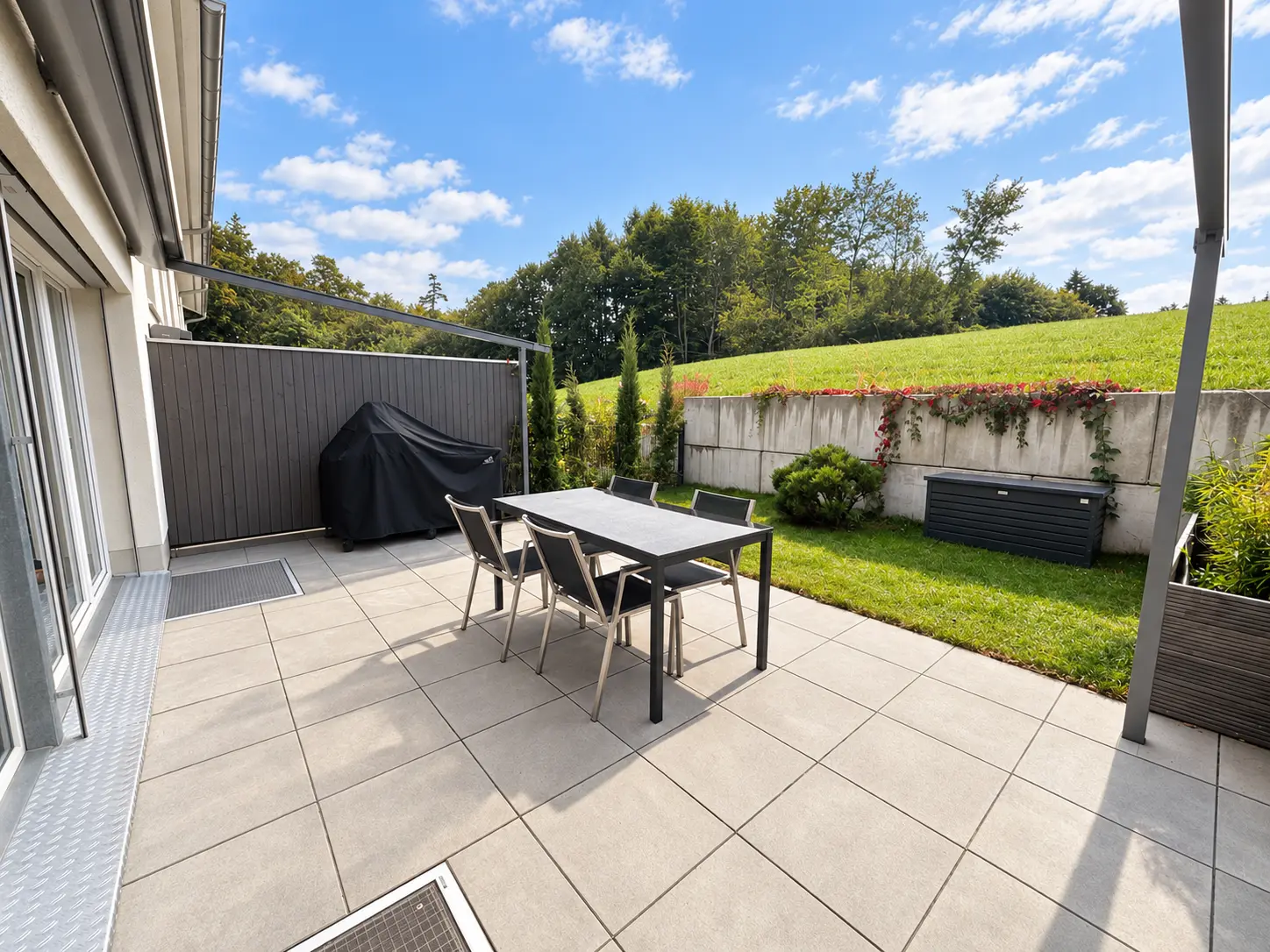 Terrasse mit Esstisch, Blick auf Rasen und Grünbewuchs